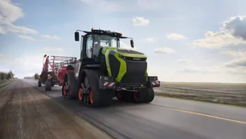 Новый стильный гусеничный трактор CLAAS XERION 12.650 на дороге общего пользования